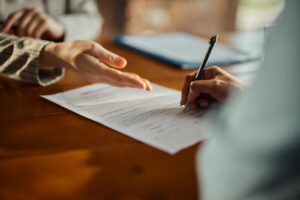 Close up of woman’s hand signing a contract during a meeting with a property manager.