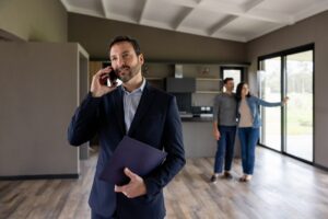 A property manager talks on the phone while showing a house.