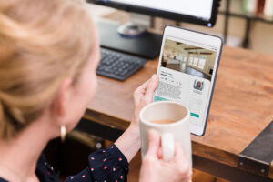 A mid adult woman looks at the interior of a home while using a mobile app on her digital tablet.
