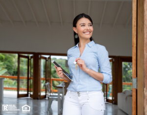 Smiling real estate agent showing a property and holding the keys and a tablet computer.