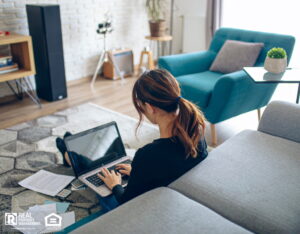 A woman at home sitting on the floor with a laptop, doing her financials.