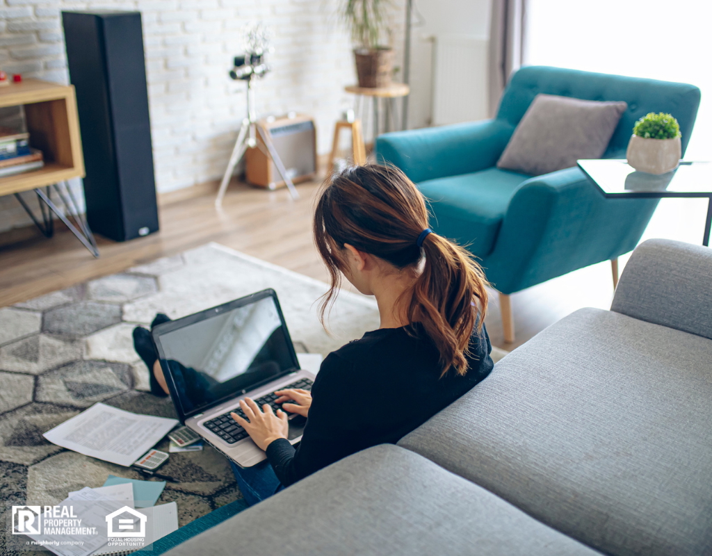 A woman at home sitting on the floor with a laptop, doing her financials.