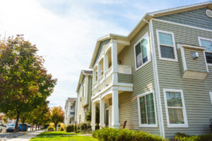 A row of multifamily houses with a sidewalk in front.