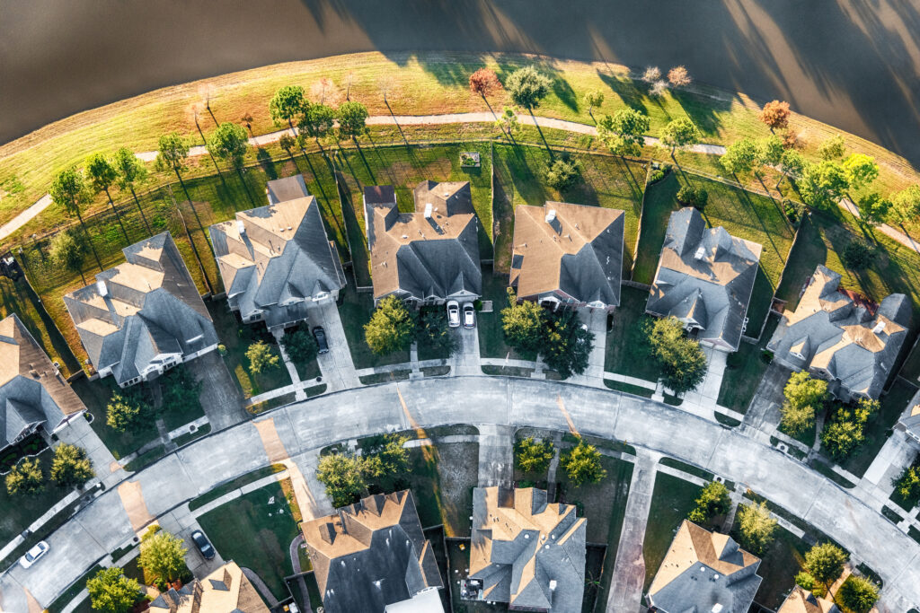 Aerial view looking directly down on a curve on a suburban street in a planned exclusive residential community in Texas.