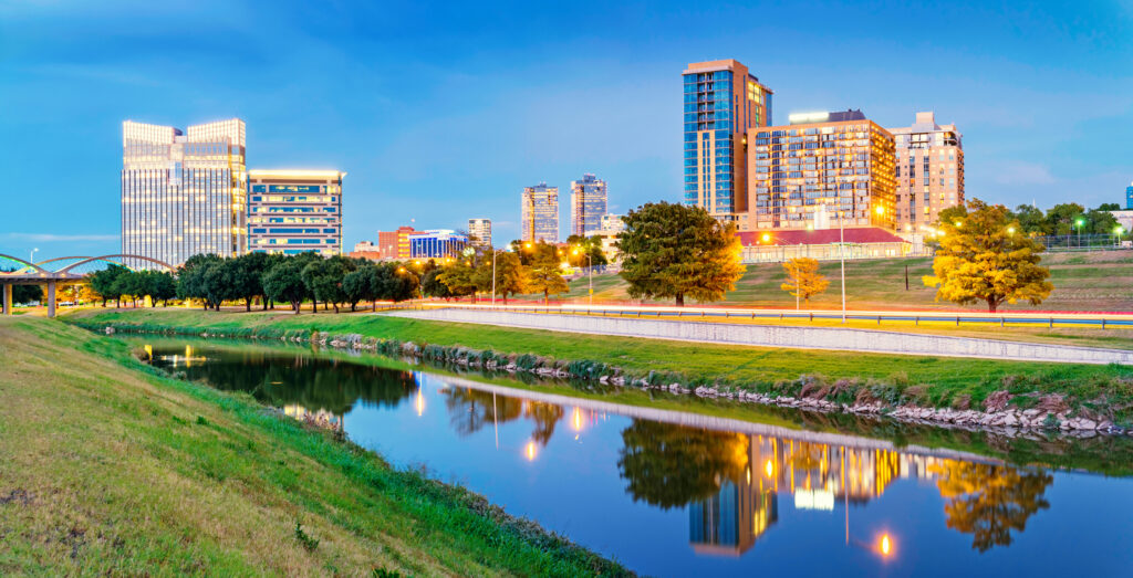 Skyline of Fort Worth, Texas; apartments and office buildings reflecting in the Clear Fork Trinity River at Trinity Park.