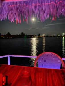 Cruisin’ Tikis Colonial Beach glowing with lights dockside at night.