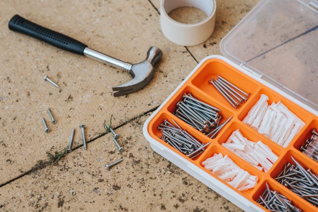 a hammer and a kit of nails on the ground
