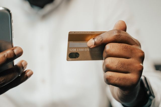 a person holding a credit card and their phone