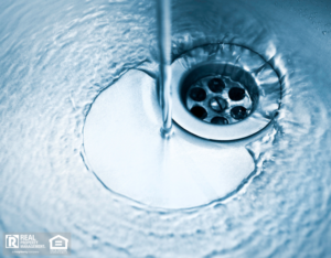 A clean sink featuring a drain and a sleek water spout.