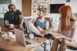 Three roommates gathered at a table in their cozy co-living space.