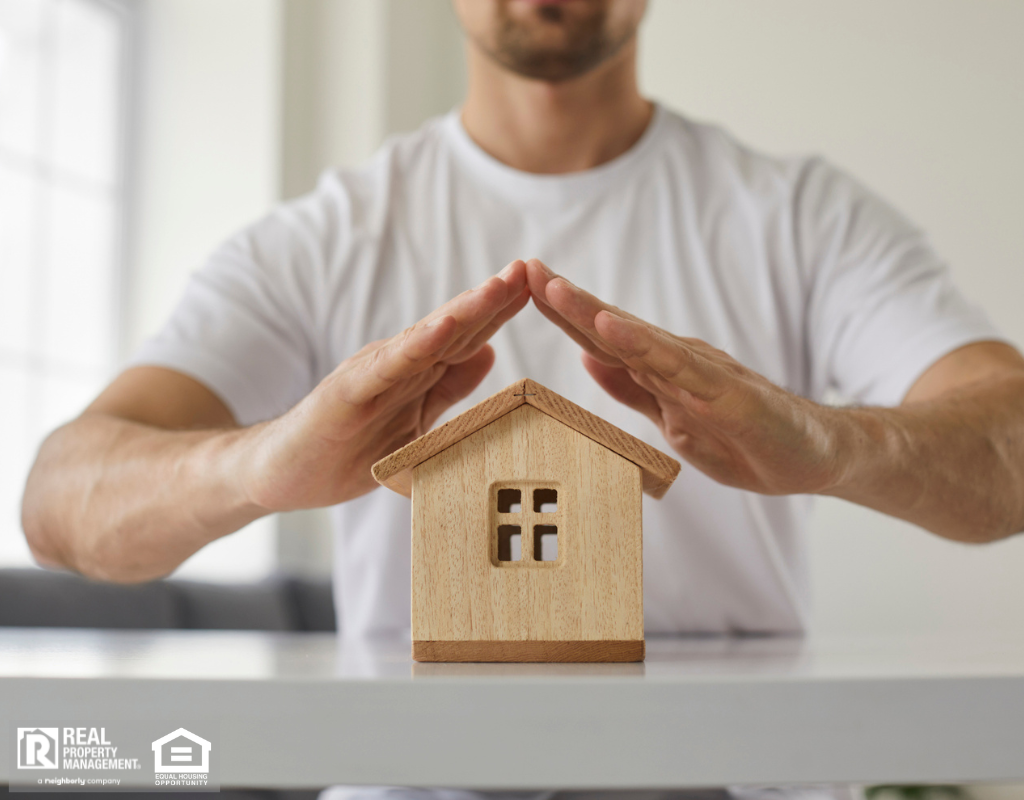 Close up of house model on table and man's hands above it, signifying home protection.