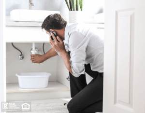 A man talking on the phone while standing in a bathroom next to a sink.