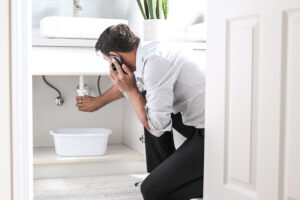 A man talking on the phone while standing in a bathroom next to a sink. 