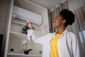 Woman turning on air conditioner with remote.