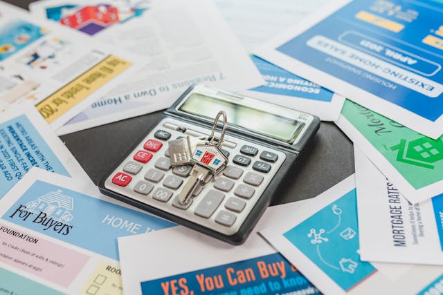 a calculator and house keys on top of investing flyers