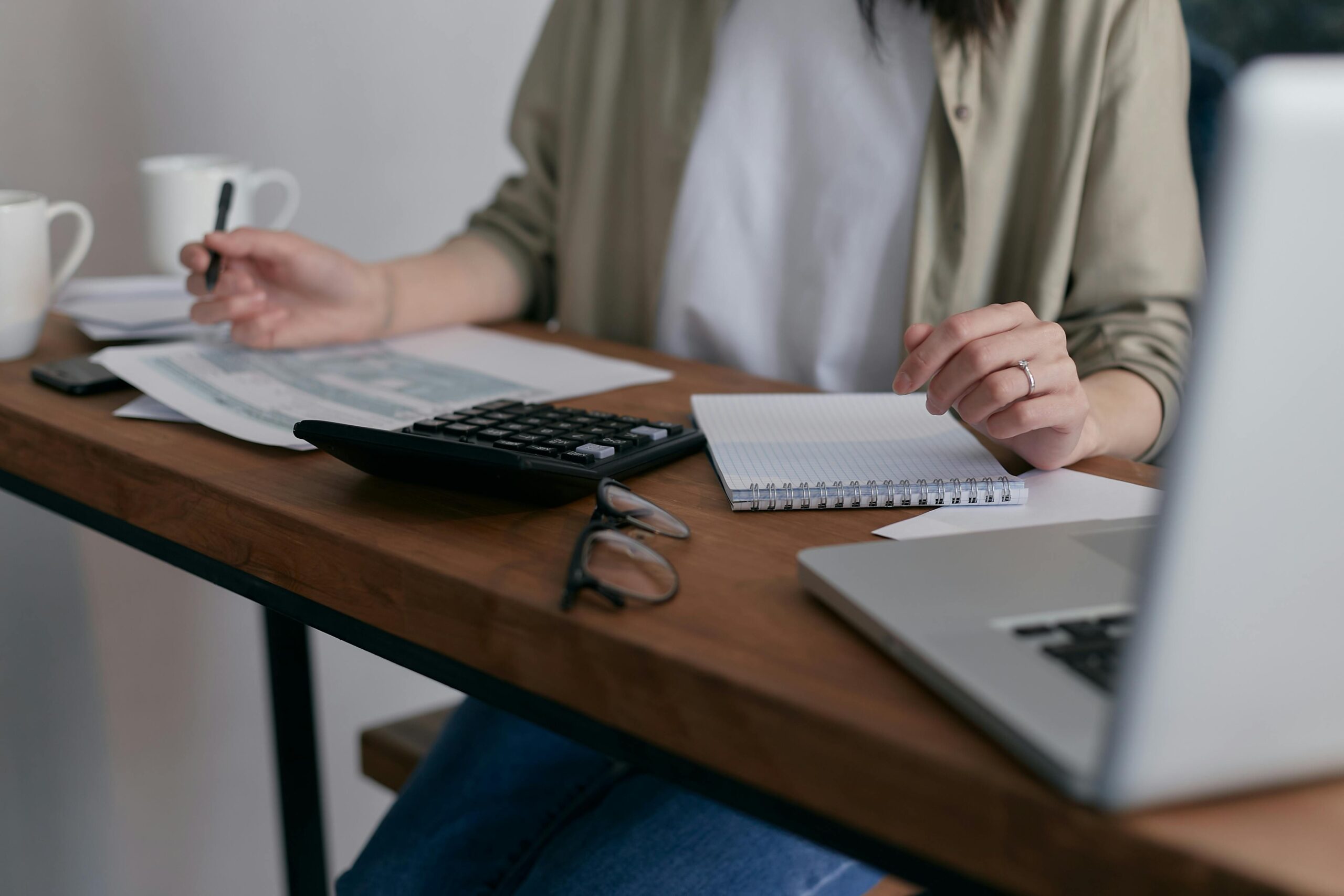 A person sitting at a desk making calculations with a calculator and notebook.