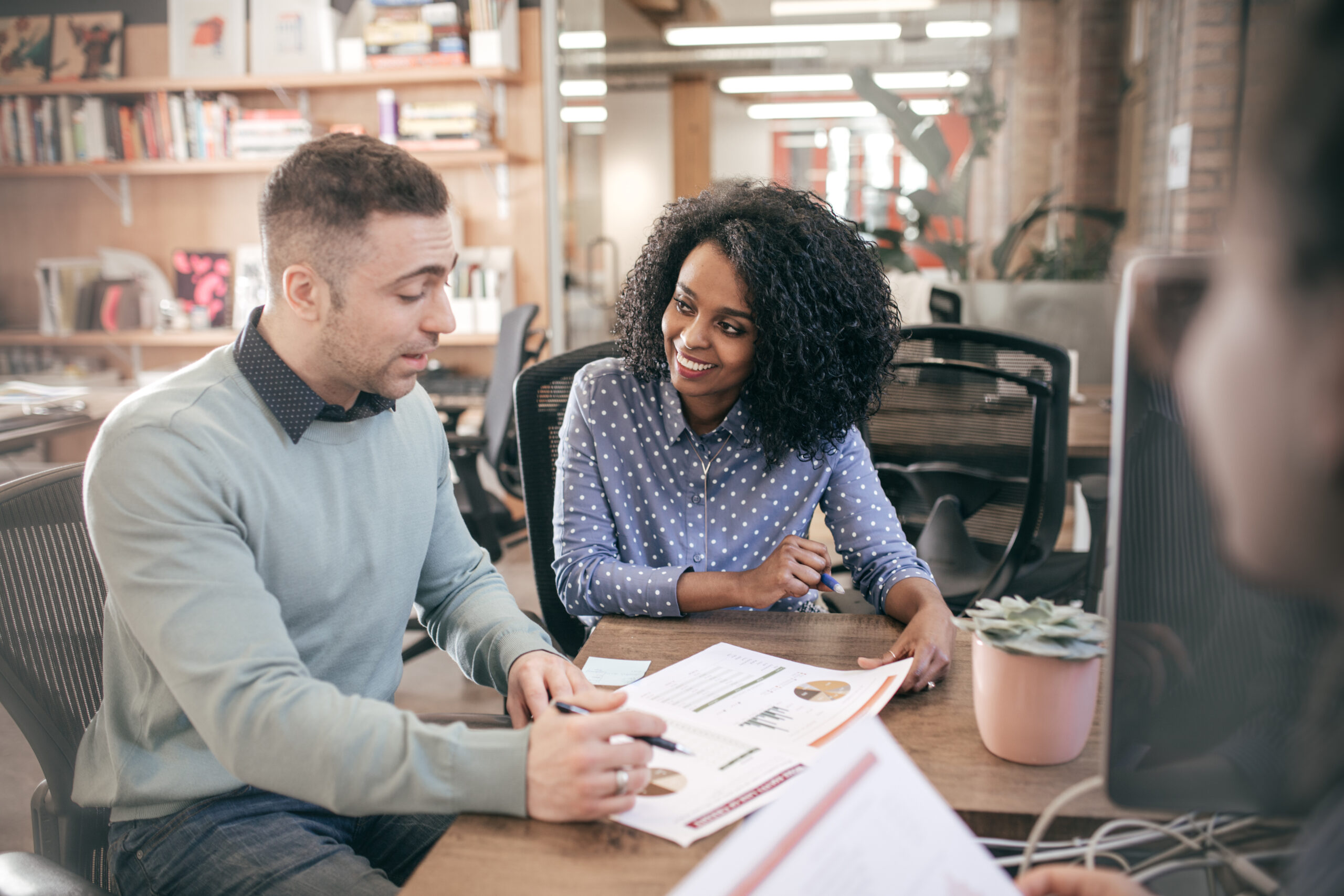 Two people sitting next to eachother at a table wile looking at graphs on a paper