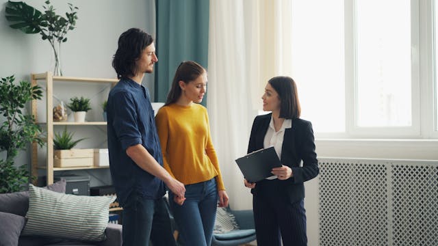a landlord smiling while speaking with two tenants
