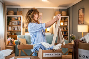 A woman sorts and puts clothes into donation boxes while decluttering her home.