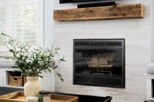 A fireplace detail with brown tiles in a cozy living room and a television mounted above.