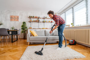 Fort Collins Renter Vacuuming an Area Rug in his Living Room