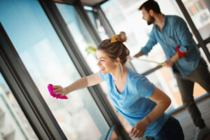 Man and woman scrubbing windows with brush.
