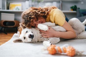A woman enjoying quality time with her dog, showing affection while lying in a comfortable rental home.