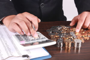 Close up of person’s hands counting money and working on a calculator. 