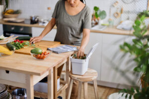 A woman putting organic waste into a compost bin. 