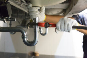 A person in white gloves diligently fixes a pipe, showcasing expertise.
