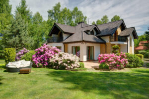 A picturesque house set against a bright spring lawn filled with colorful flowers.