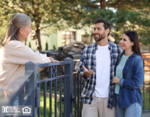 Young couple talking to senior woman near fence outdoors.
