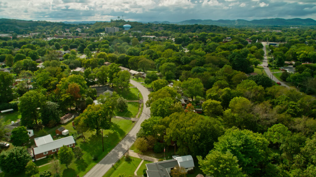 Aerial shot of a residential neighborhood in the southern suburbs of Nashville, Tennessee, with a view across the thickly wooded rolling landscape towards the foothills of the Appalachian Mountains.