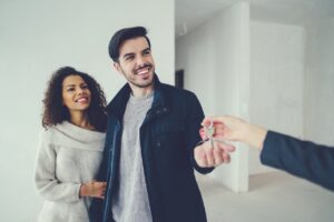 A couple smiles as they proudly display keys to their new rental house.