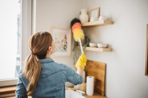 Resident dusting a surface at rental home kitchen.