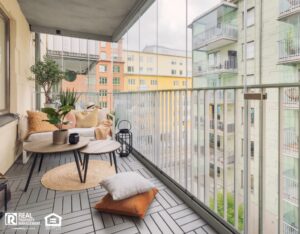 A balcony decorated with comfortable chairs, plants, and lighting.