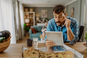 A confused man staring at his tablet.