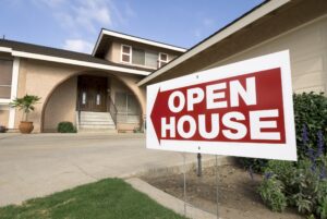 An "Open House" sign is displayed in front of a charming house, signaling an event for potential buyers.