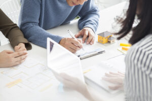 People sitting at a table signing a lease renewal agreement.
