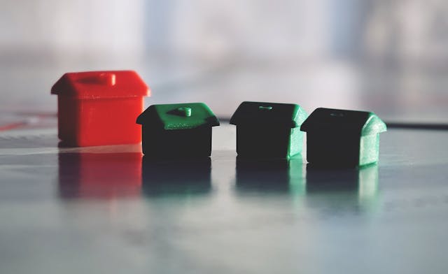 toy-houses-arranged-as-a-neighborhood-with-one-large-red-house-and-three-smaller-green-ones