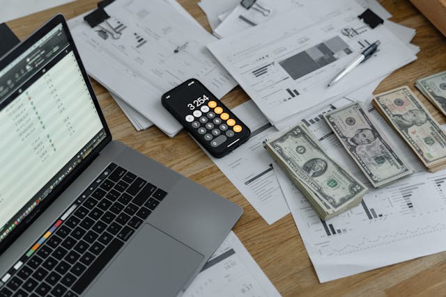 cluttered-desk-with-documents-laptop-calculator-app-and-cash