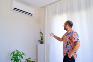 Man adjusts air conditioner for fresher indoor air.