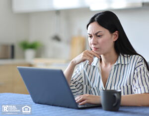 Suspicious landlord using a laptop to review rental applications.
