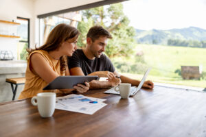 A man and woman at a table reviewing rental property data on a laptop surrounded by papers.
