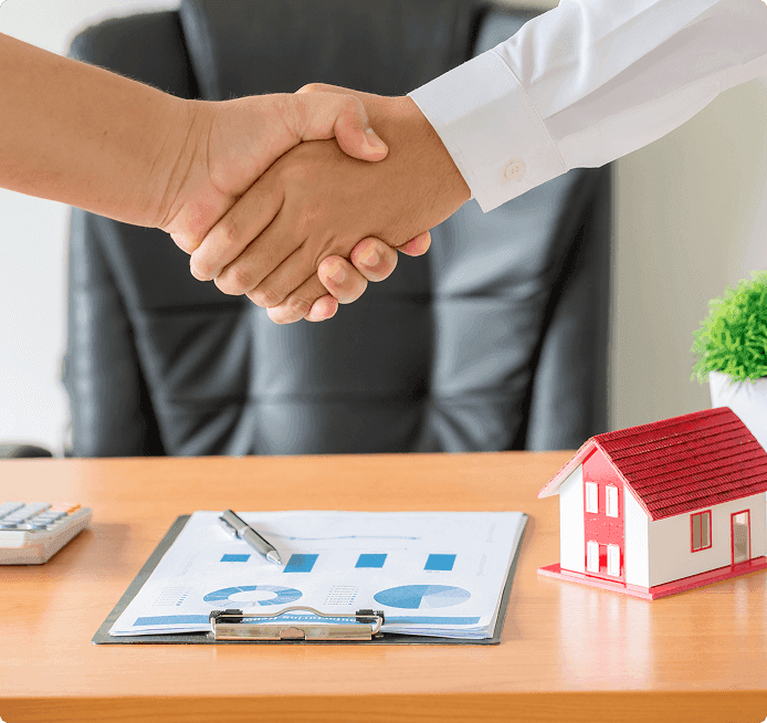 two people shaking hands over a desk