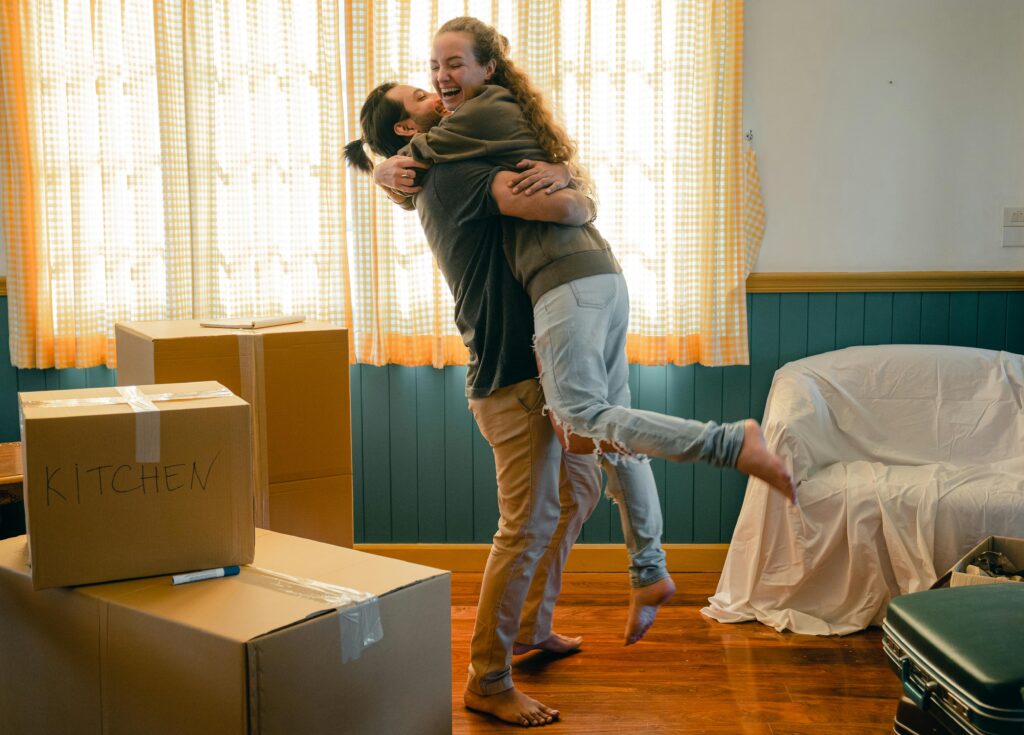 people with moving boxes hugging in house