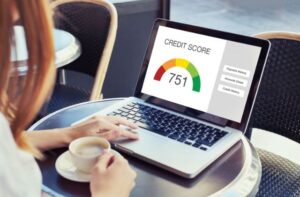 Person reviewing a tenant’s credit score on a laptop while drinking coffee.