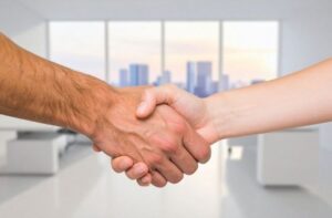 Landlord and tenant shaking hands in a bright office after a successful screening.