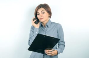 Property manager speaking on the phone while reviewing a rental application on a clipboard.