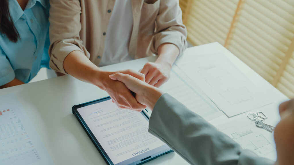 Close-up of Asian tenants sign house agreements on tablet and give them to female real estate agent after showing new houses. Landlord selling real estate to customers for investment.